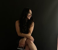 a woman in a black dress sitting on a stool